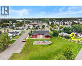 A bird's eye view of a residential area with a large grassy area and a red building in the center.