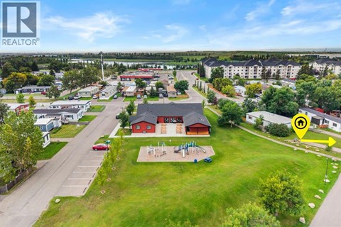 A bird's eye view of a residential area with a large grassy area and a red building in the center.