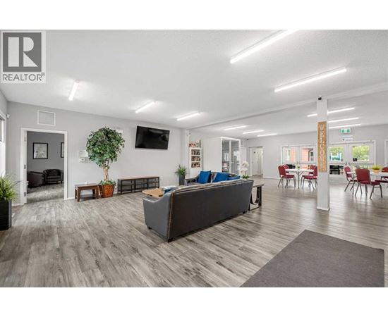 A spacious living room with a grey sofa and a wooden floor.