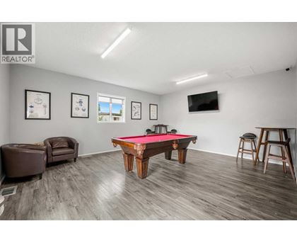 A room with a pool table and a tv mounted on the wall.