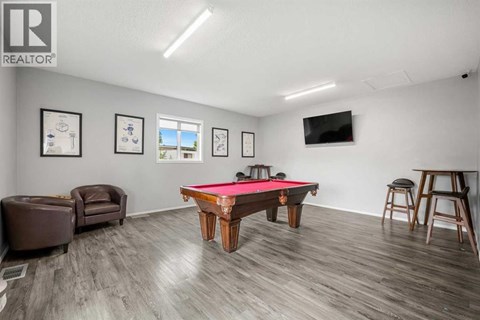 A room with a pool table and a tv mounted on the wall.