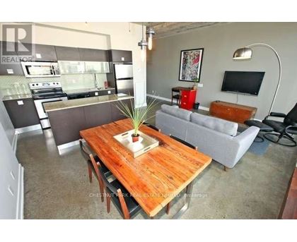 A living room with a wooden table in the center and a grey couch.