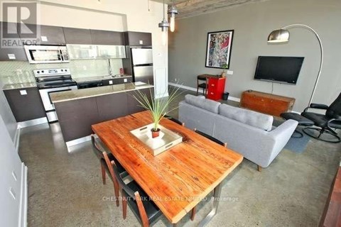 A living room with a wooden table in the center and a grey couch.