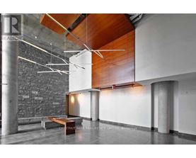 A modern interior space with a bench, a wall, and a ceiling with wooden beams.