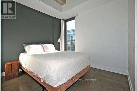 A bedroom with a bed, pillows, and a nightstand.