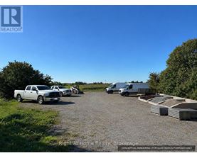 A gravel lot with a truck, a van, and a trailer.