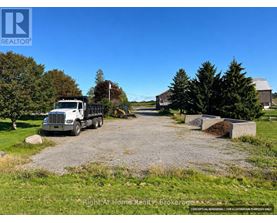 A gravel driveway leads to a house with a truck parked in front.