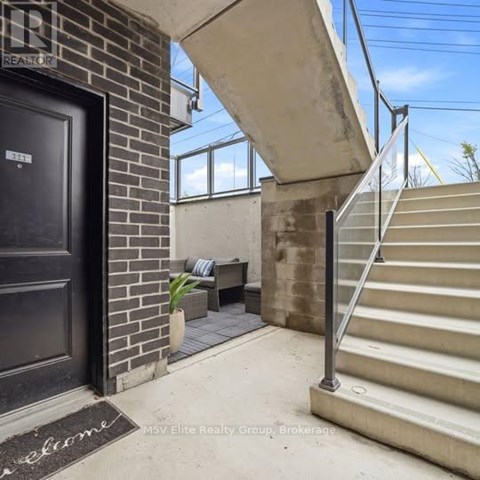 A black door with a welcome mat in front of a brick wall.
