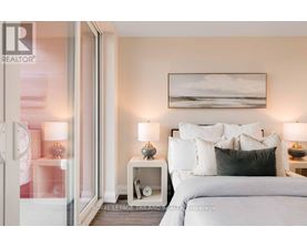 A bedroom with a large bed, two nightstands with lamps, and a painting on the wall.
