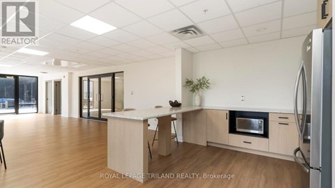 A kitchen with a refrigerator, microwave, and a dining table with chairs.