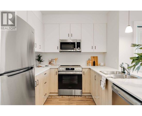 A modern kitchen with a refrigerator, oven, microwave, and cabinets.