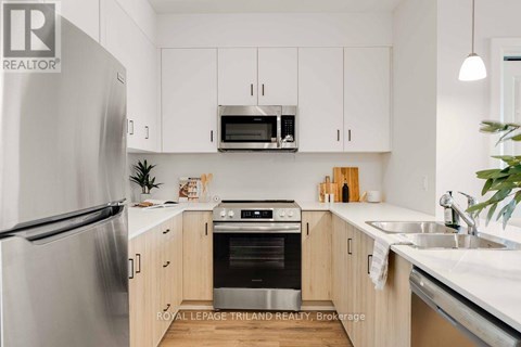 A modern kitchen with a refrigerator, oven, microwave, and cabinets.