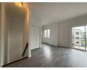 A spacious room with wooden flooring and white walls.