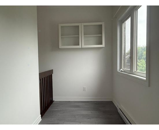 A room with a window and a cabinet above it.