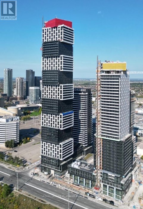 A tall building with a red roof is under construction in a city.