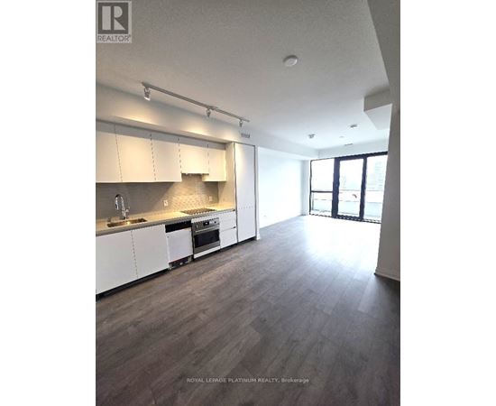 A spacious kitchen with white cabinets and a wooden floor.
