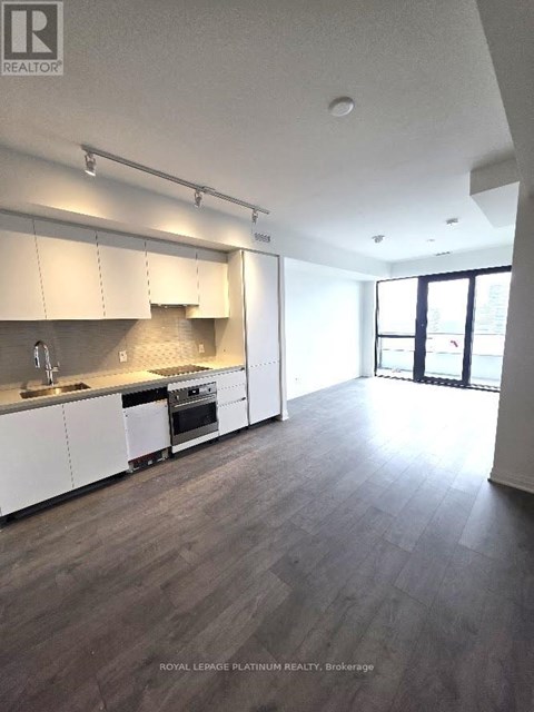 A spacious kitchen with white cabinets and a wooden floor.