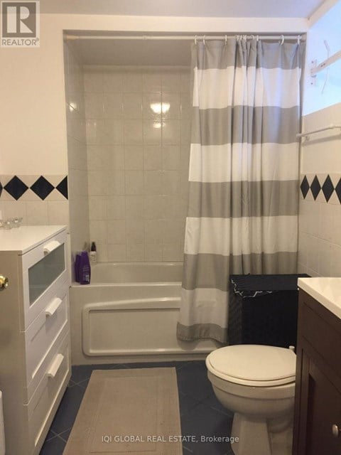 A bathroom with a toilet, a bathtub, and a shower curtain.