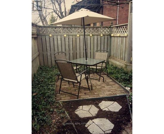 A patio with a table and chairs and a fence.