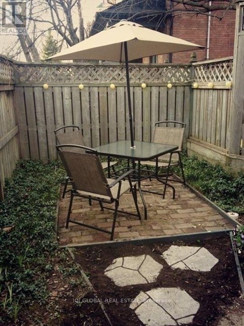 A patio with a table and chairs and a fence.