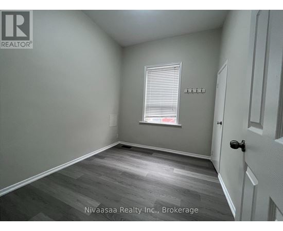 A room with a door, a window with blinds, and a wall with a logo.