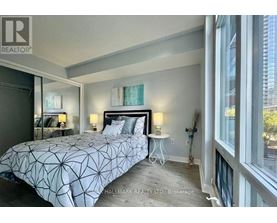 A bedroom with a large bed and a window overlooking a city.