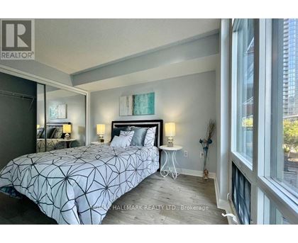 A bedroom with a large bed and a window overlooking a city.