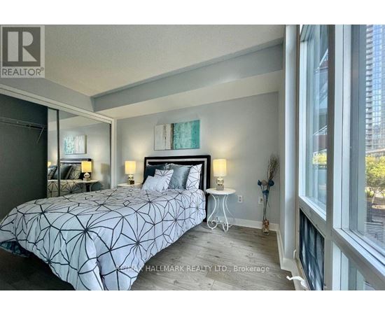 A bedroom with a large bed and a window overlooking a city.