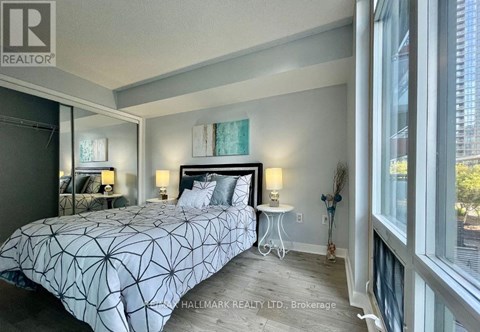 A bedroom with a large bed and a window overlooking a city.