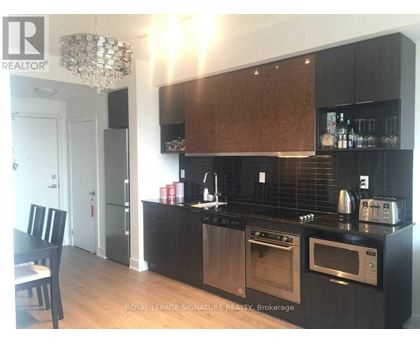 A modern kitchen with dark wood cabinets and stainless steel appliances.