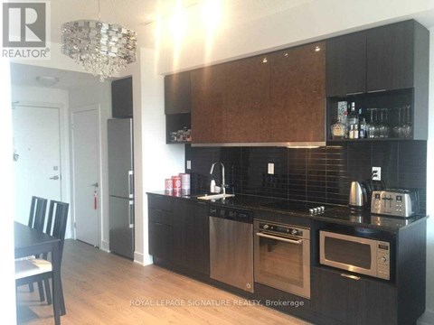 A modern kitchen with dark wood cabinets and stainless steel appliances.
