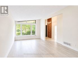 A room with white walls and wooden flooring, with a window and a door visible.