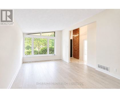 A room with white walls and wooden flooring, with a window and a door visible.