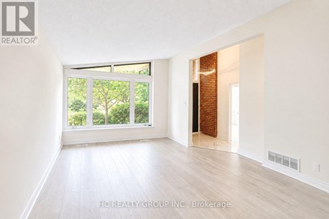 A room with white walls and wooden flooring, with a window and a door visible.