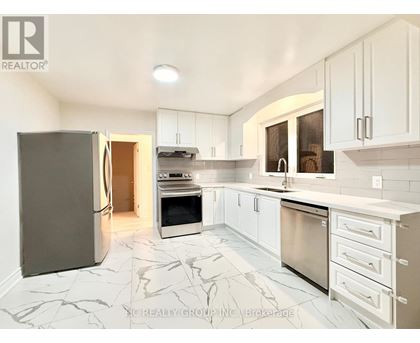 A kitchen with white cabinets and marble tiles.