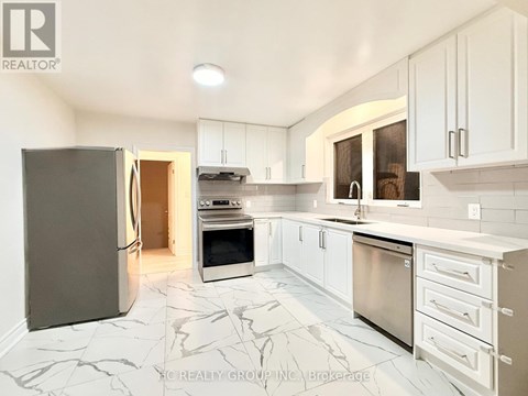 A kitchen with white cabinets and marble tiles.