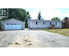A house with a garage is situated in a driveway.