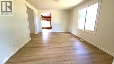 A spacious room with wooden flooring and white walls.