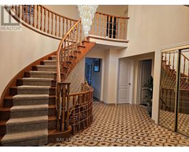 A staircase with a wooden banister and a chandelier hanging from the ceiling.