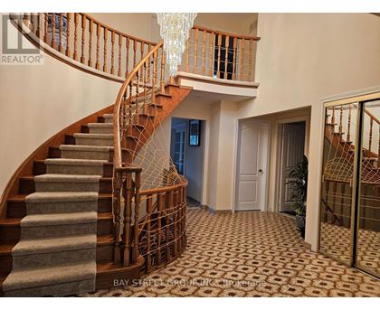 A staircase with a wooden banister and a chandelier hanging from the ceiling.