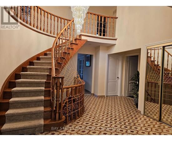 A staircase with a wooden banister and a chandelier hanging from the ceiling.