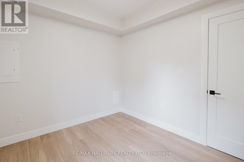 A white room with a wooden floor and a door on the right side.
