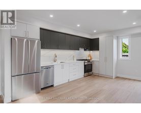 A modern kitchen with a refrigerator, sink, and stove.