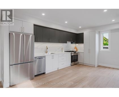 A modern kitchen with a refrigerator, sink, and stove.
