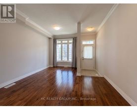 A room with wooden floors and white walls, with a window and a door visible.