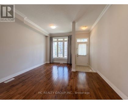 A room with wooden floors and white walls, with a window and a door visible.