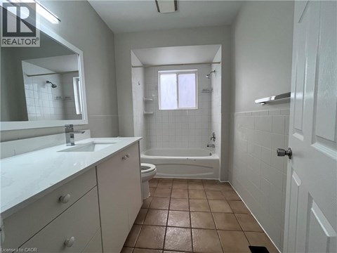 A bathroom with a white counter top and brown floor tiles.