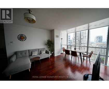 A living room with a grey couch and a clock on the wall.