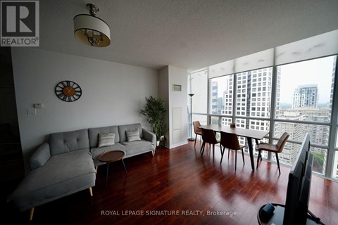 A living room with a grey couch and a clock on the wall.