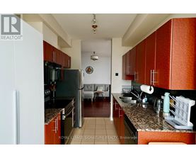 A kitchen with brown cabinets and a black refrigerator.